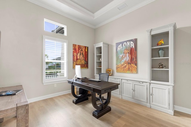 home office with ornamental molding, light wood-type flooring, and a tray ceiling