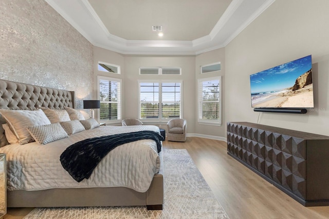 bedroom with crown molding, a raised ceiling, light hardwood / wood-style flooring, and a high ceiling