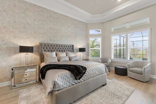 bedroom with a high ceiling, wood-type flooring, crown molding, and a tray ceiling