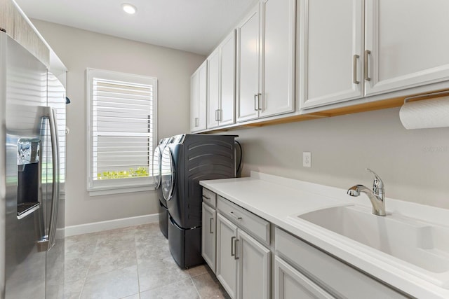 washroom with cabinets, light tile patterned flooring, sink, and washing machine and clothes dryer