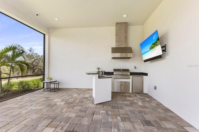 kitchen with sink, a patio area, refrigerator, exterior kitchen, and wall chimney range hood