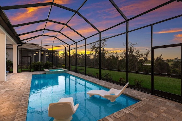 pool at dusk with an in ground hot tub, a water slide, a lanai, and a patio