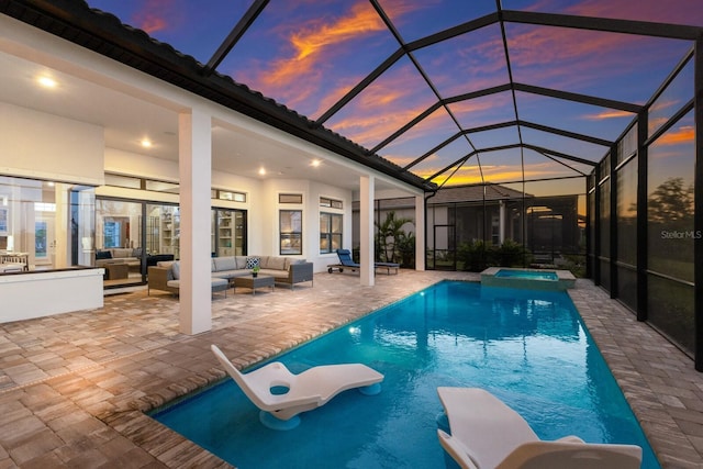 pool at dusk with an outdoor living space, a water slide, a patio, and glass enclosure