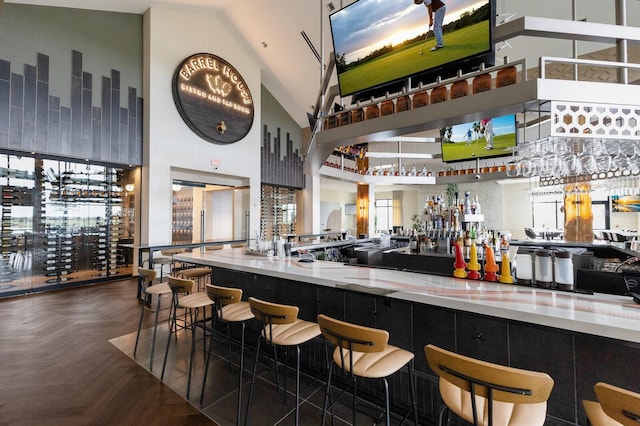 bar with high vaulted ceiling, a wealth of natural light, and dark parquet floors