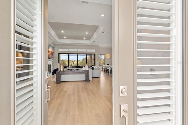 entryway featuring crown molding, a tray ceiling, light hardwood / wood-style floors, and beverage cooler