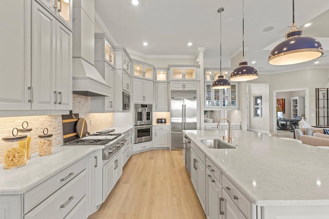 kitchen with built in appliances, sink, decorative light fixtures, and custom range hood