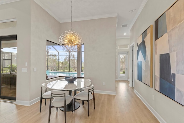 dining room with an inviting chandelier, crown molding, and light hardwood / wood-style floors