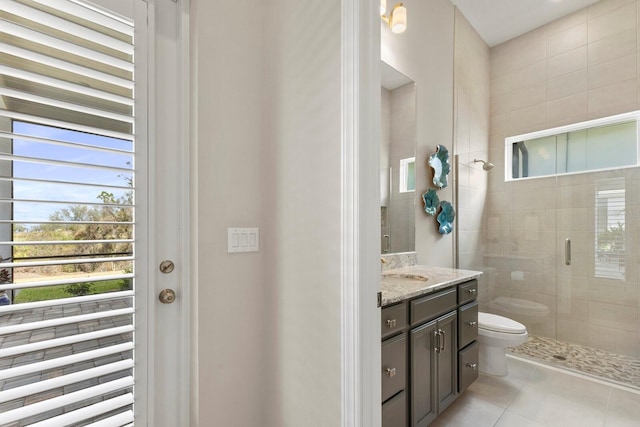 bathroom with vanity, toilet, a shower with shower door, and tile patterned flooring