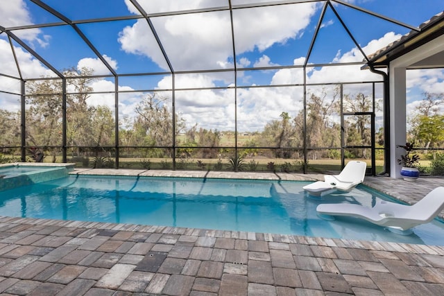 view of pool with a patio area, an in ground hot tub, and glass enclosure