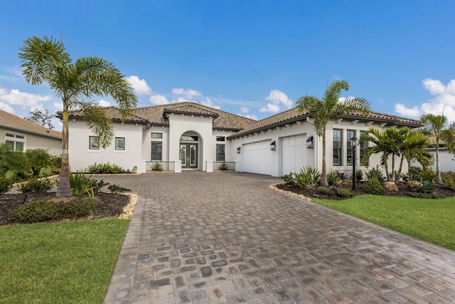 mediterranean / spanish-style home with stucco siding, french doors, decorative driveway, a tile roof, and a garage