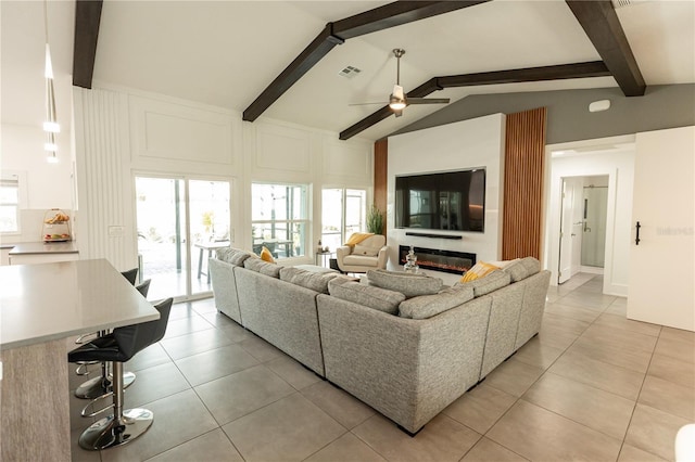 living room with light tile patterned floors, visible vents, a glass covered fireplace, ceiling fan, and vaulted ceiling with beams