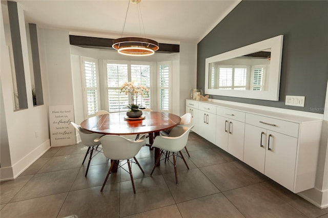 dining area with lofted ceiling, baseboards, and dark tile patterned flooring