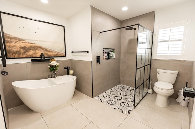 full bathroom featuring tile walls, a freestanding bath, toilet, tile patterned flooring, and walk in shower