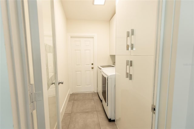 laundry area featuring washer and clothes dryer, light tile patterned flooring, cabinet space, and baseboards