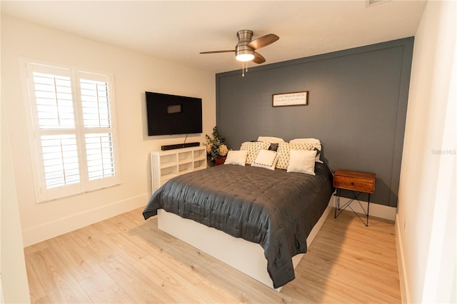 bedroom featuring ceiling fan, baseboards, and wood finished floors