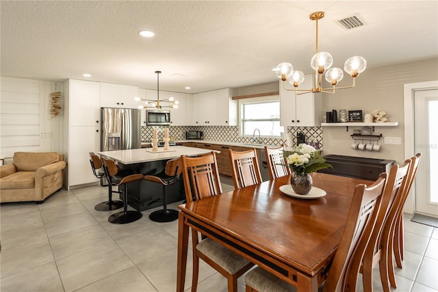 dining area featuring a textured ceiling, light tile patterned flooring, recessed lighting, visible vents, and an inviting chandelier