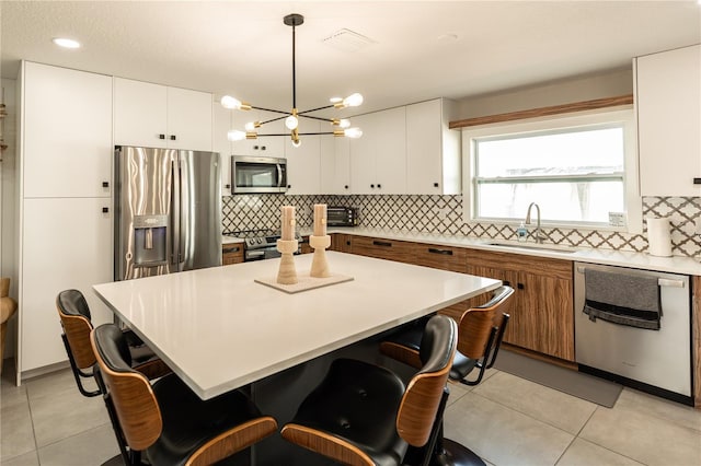 kitchen with light tile patterned floors, stainless steel appliances, a sink, and a kitchen breakfast bar