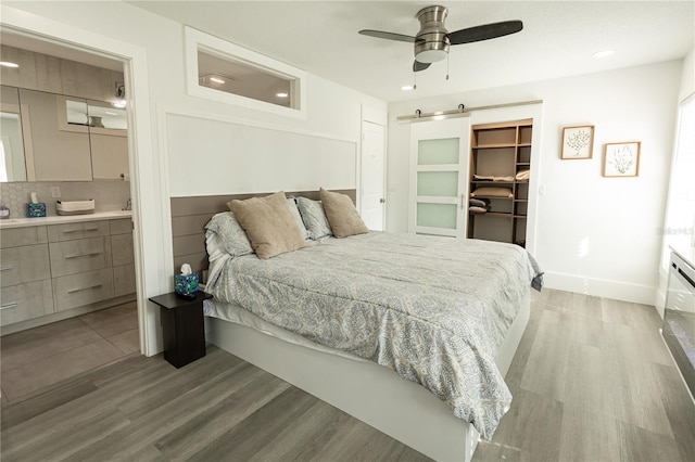 bedroom featuring a closet, a spacious closet, light wood finished floors, and a barn door