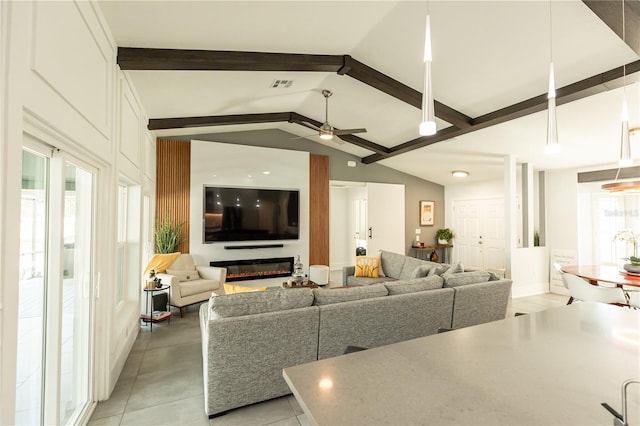 living area with visible vents, a ceiling fan, a glass covered fireplace, lofted ceiling with beams, and light tile patterned flooring