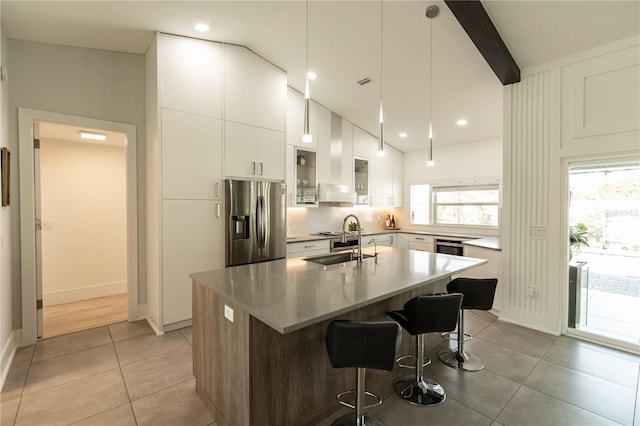 kitchen with beam ceiling, a breakfast bar area, light tile patterned flooring, a sink, and stainless steel fridge with ice dispenser