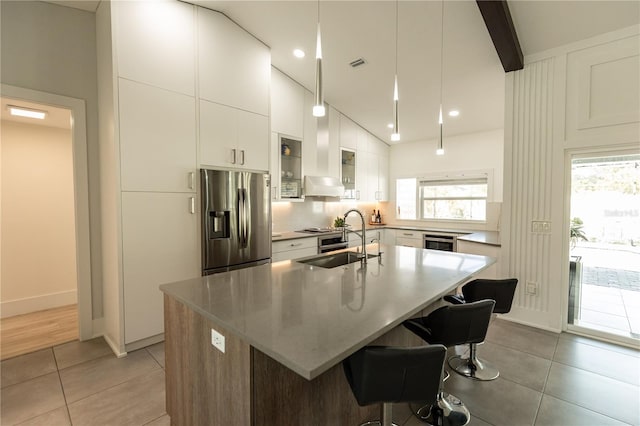 kitchen featuring a wealth of natural light, light tile patterned flooring, a sink, beverage cooler, and stainless steel fridge