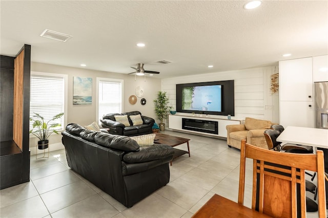 living area with a textured ceiling, light tile patterned floors, visible vents, and recessed lighting