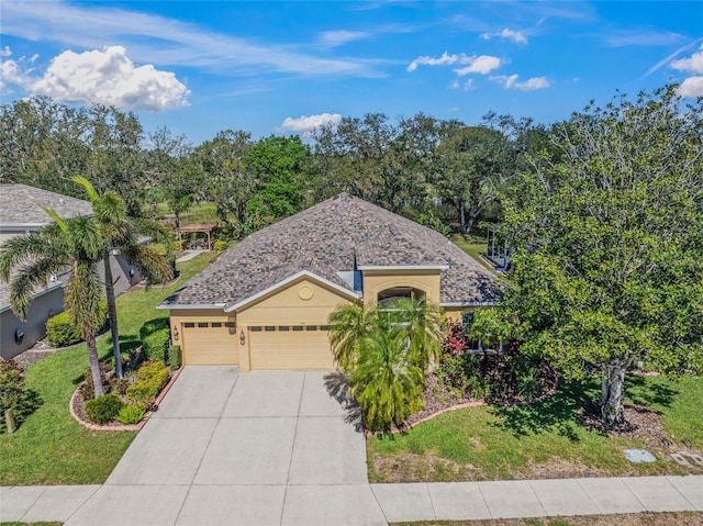 view of front facade with stucco siding, driveway, a front lawn, an attached garage, and a shingled roof