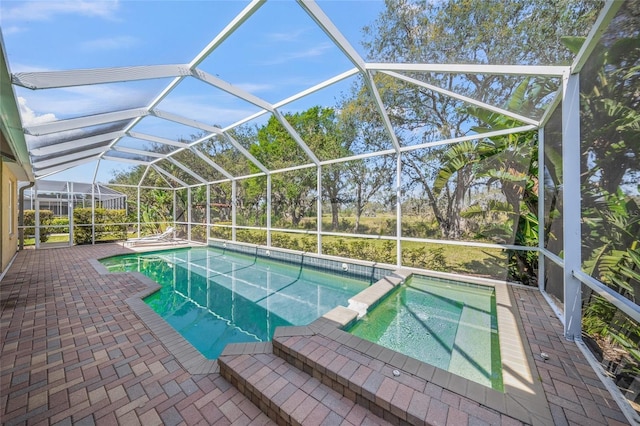 view of pool with glass enclosure, a patio, and a pool with connected hot tub