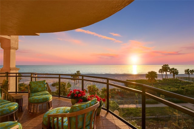 balcony at dusk featuring a water view