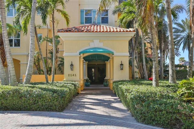 view of exterior entry featuring a tiled roof and stucco siding