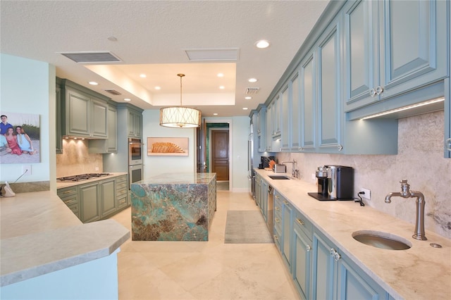 kitchen with sink, a tray ceiling, decorative light fixtures, and stainless steel appliances