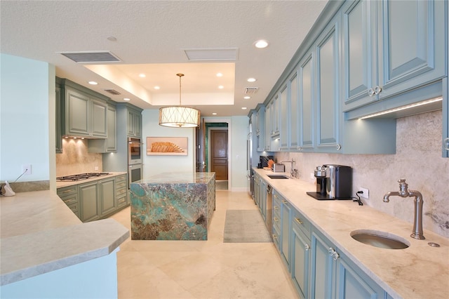 kitchen with a sink, a tray ceiling, visible vents, and stainless steel appliances