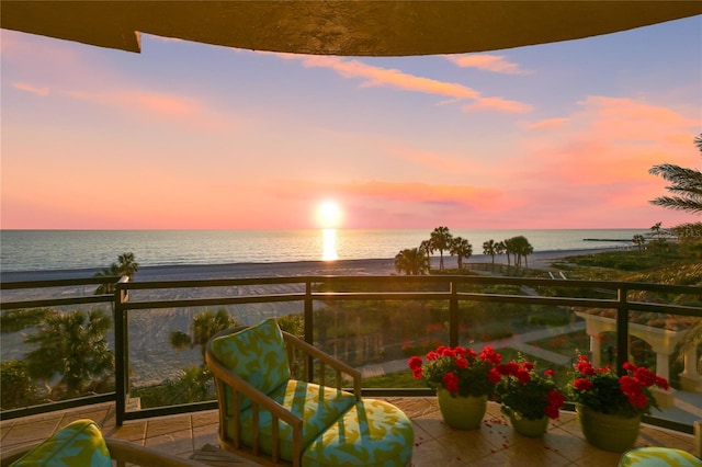 balcony at dusk featuring a water view