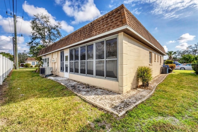 view of property exterior with a yard and central air condition unit