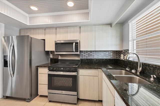 kitchen with sink, a tray ceiling, light tile patterned floors, and appliances with stainless steel finishes