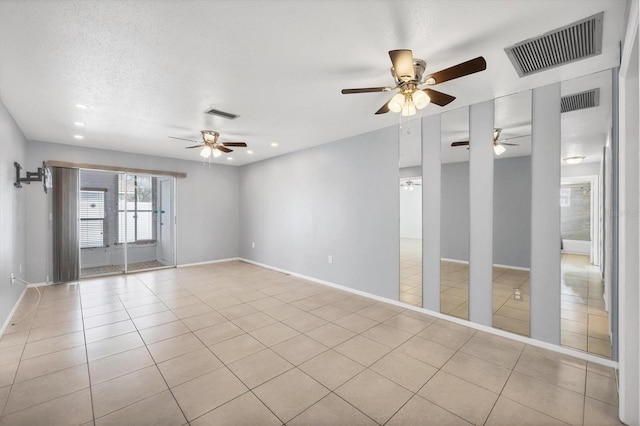 empty room featuring ceiling fan, light tile patterned floors, and a textured ceiling