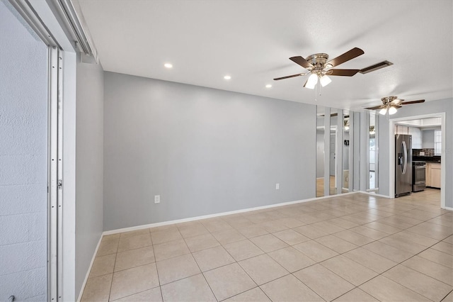 empty room with ceiling fan and light tile patterned floors