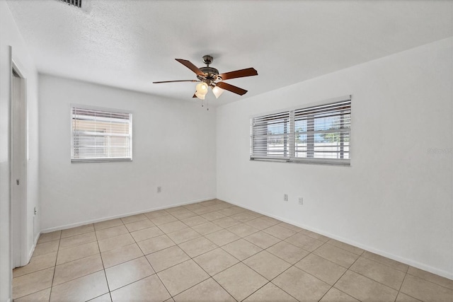 tiled spare room with a textured ceiling and ceiling fan