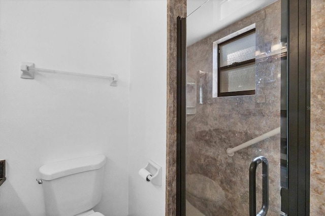 bathroom with a shower with door and toilet