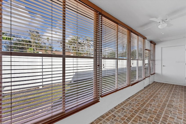 unfurnished sunroom featuring a healthy amount of sunlight and ceiling fan