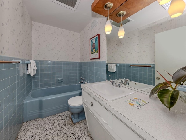 bathroom featuring vanity, toilet, a bathtub, and tile walls