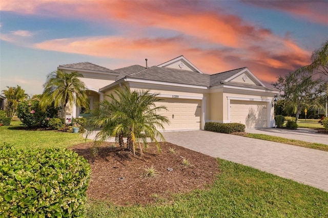 view of front facade with an attached garage, a lawn, decorative driveway, and stucco siding