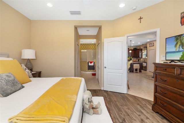 bedroom with connected bathroom and hardwood / wood-style flooring