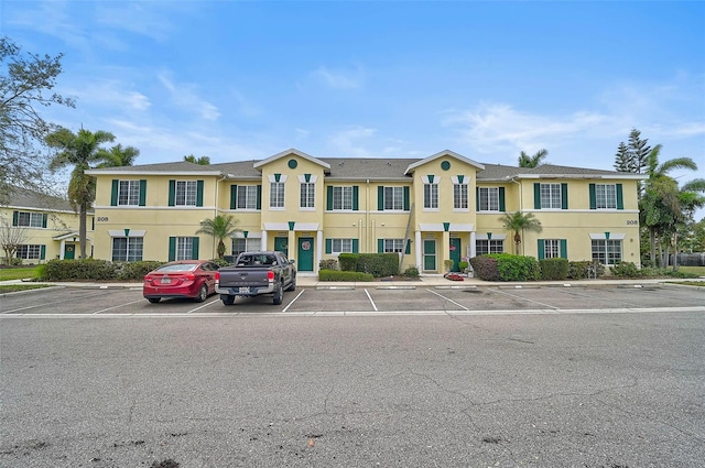 view of property with uncovered parking and stucco siding