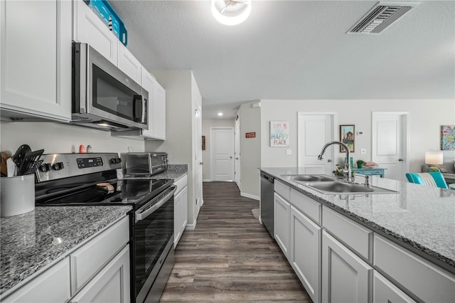 kitchen with sink, dark wood-type flooring, appliances with stainless steel finishes, a textured ceiling, and white cabinets