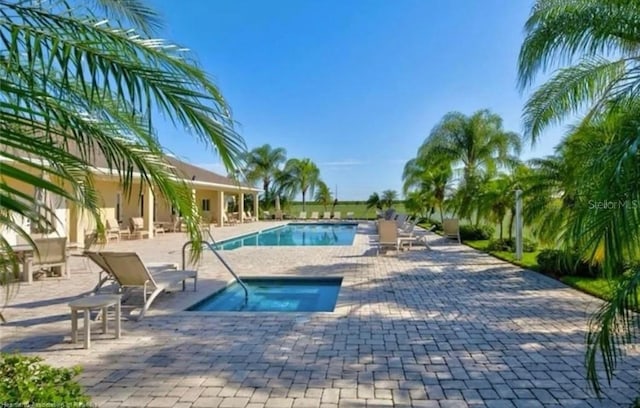 view of swimming pool with a hot tub and a patio