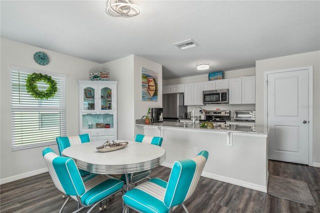 dining space featuring dark wood-type flooring, visible vents, a toaster, and baseboards