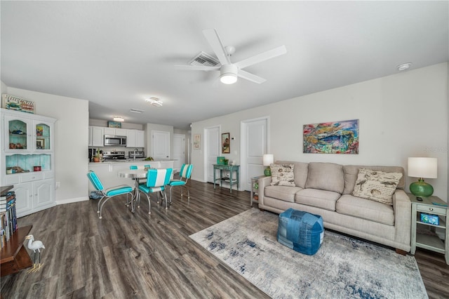 living room featuring a ceiling fan, visible vents, and dark wood-style floors