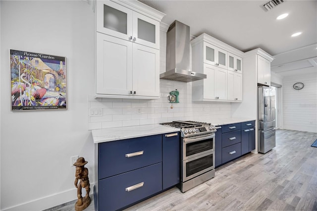 432 W Gate Dr, Venice, FL 34285 - kitchen featuring light wood-style flooring, stainless steel appliances, visible vents, wall chimney range hood, and blue cabinetry