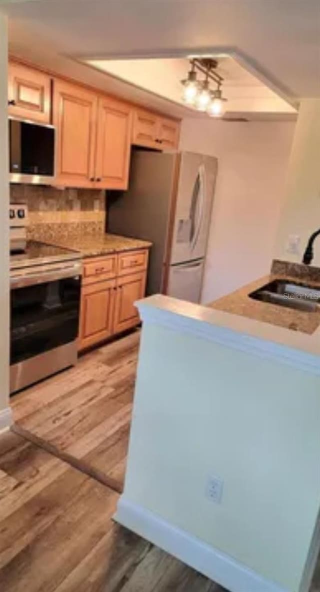 625 Duchess Blvd, Dunedin, FL 34698 - kitchen with appliances with stainless steel finishes, light wood-type flooring, decorative backsplash, light brown cabinetry, and light countertops